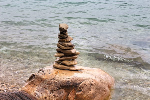 flat rocks balanced on large boulders in lake michigan with a wave