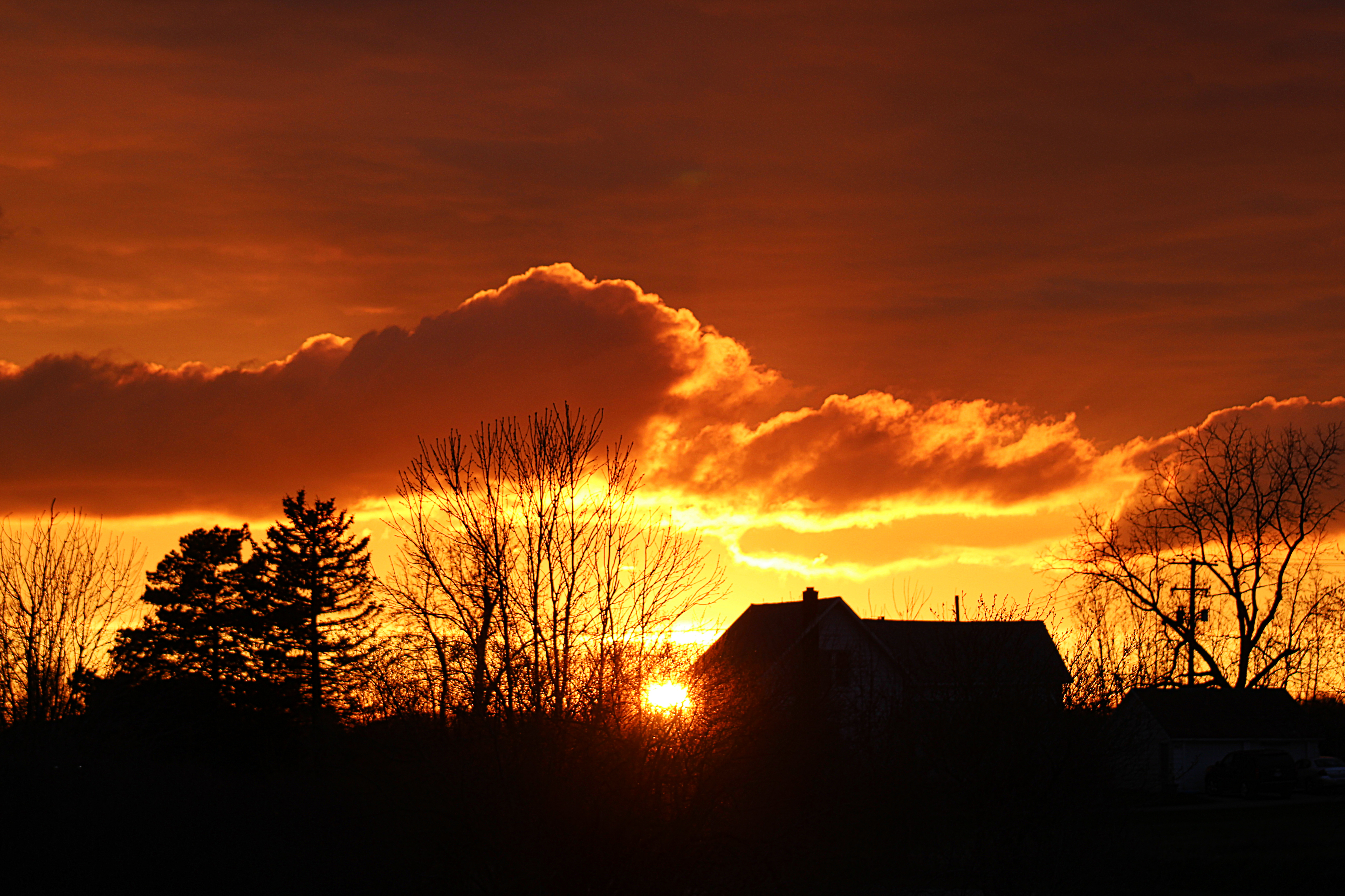 the sky is on fire in this sunset behind a farmhouse