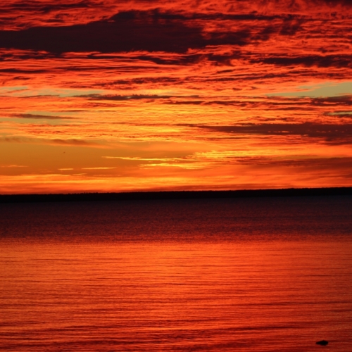 blazing red sunrise on lake huron reflecting off the water