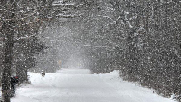 snowing heavily on country road with care lights barely seen in the distance