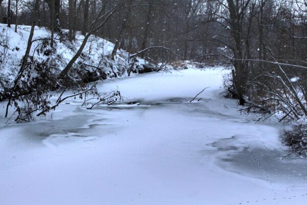 snows falls on an ice covered river